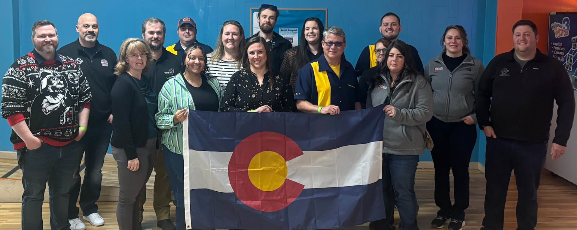 Photo of dispatch employees holding Colorado state flag after earning award